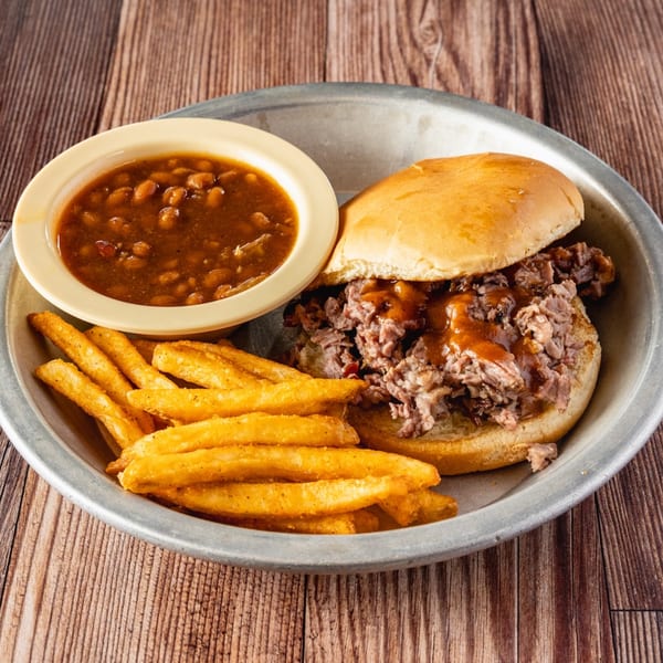 Bowie Barbeque pulled pork sandwich with fries and baked beans on a metal plate.