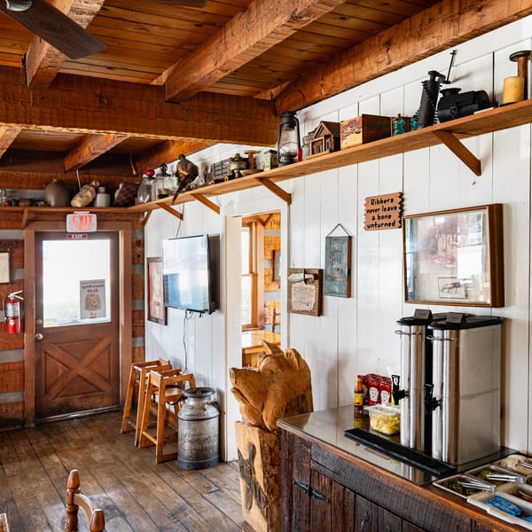 Rustic Bowie Barbeque interior with wooden beams, white walls, and a drink station with a pig carving.