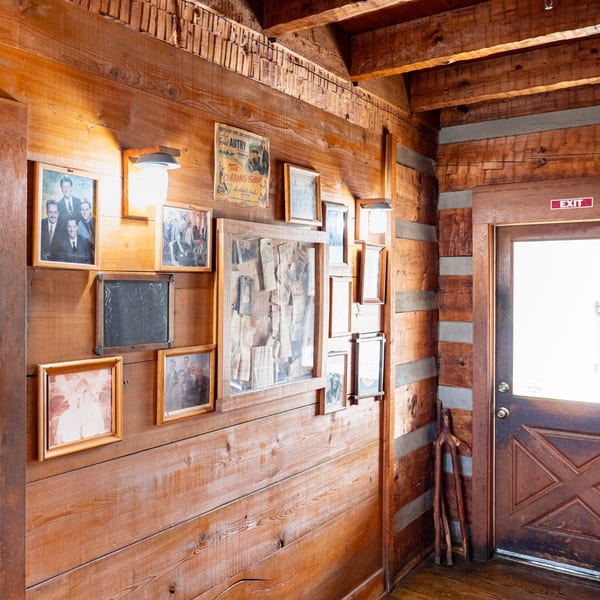 Rustic wooden wall at Bowie Barbeque adorned with framed photos, a movie poster, and an exit door.