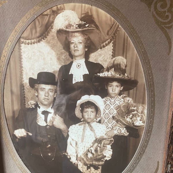 Sepia-toned portrait of a family of four in period Western attire, framed in an ornate oval.